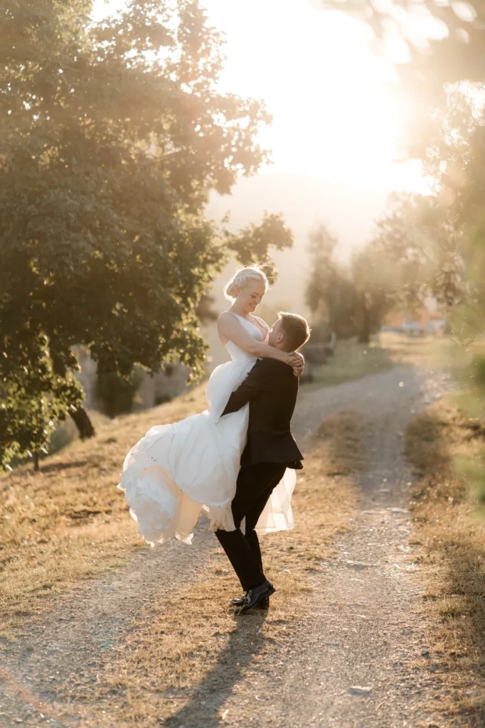 The groom lifting the bride against the evening light, Castello del Trebbio